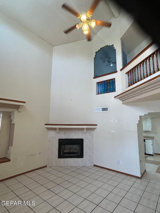 12014 El Greco Cir, El Paso, TX 79936 - unfurnished living room featuring a ceiling fan, light tile patterned flooring, a tile fireplace, baseboards, and a high ceiling