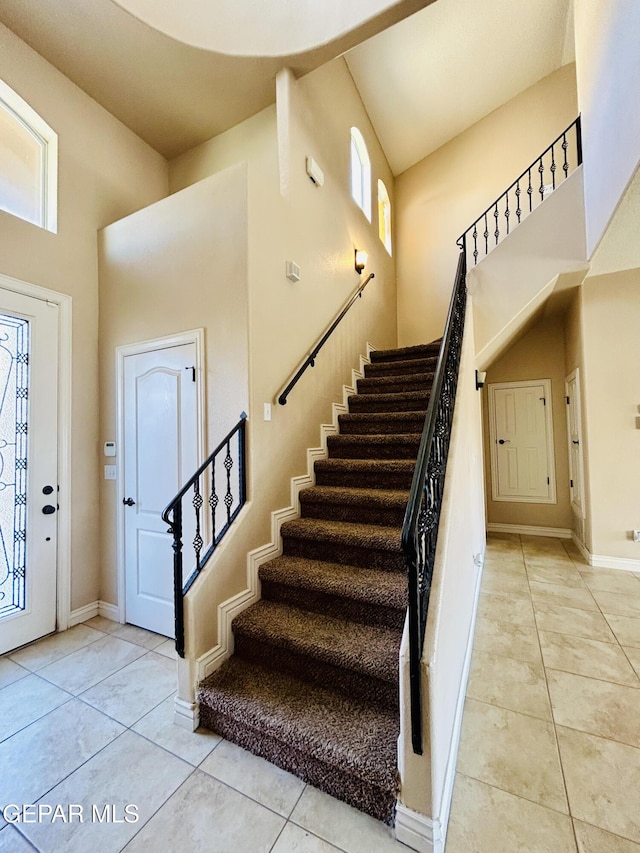 11609 Saint Thomas Way, El Paso, TX 79936 - foyer entrance featuring a towering ceiling, stairway, light tile patterned floors, and baseboards