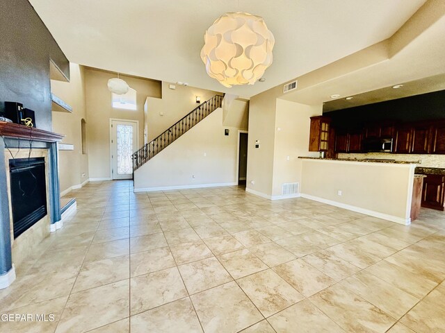 11609 Saint Thomas Way, El Paso, TX 79936 - unfurnished living room featuring stairs, a fireplace, and light tile patterned flooring