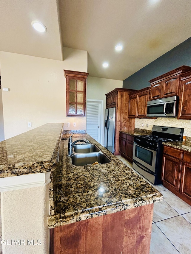 11609 Saint Thomas Way, El Paso, TX 79936 - kitchen with appliances with stainless steel finishes, a sink, decorative backsplash, dark stone counters, and a center island with sink