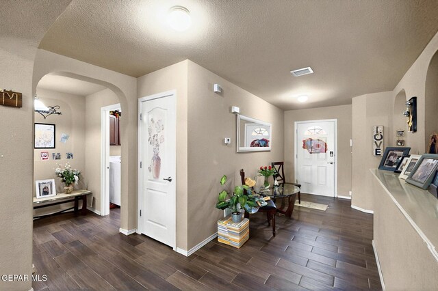 12009 Copper Point Pl, El Paso, TX 79934 - foyer featuring arched walkways, dark wood-style floors, a textured ceiling, baseboards, and washer / clothes dryer