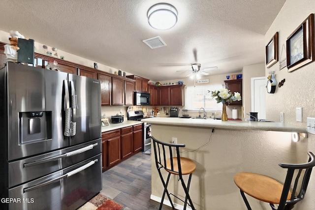 12009 Copper Point Pl, El Paso, TX 79934 - kitchen with stainless steel appliances, a textured ceiling, a breakfast bar area, ceiling fan, and a textured wall
