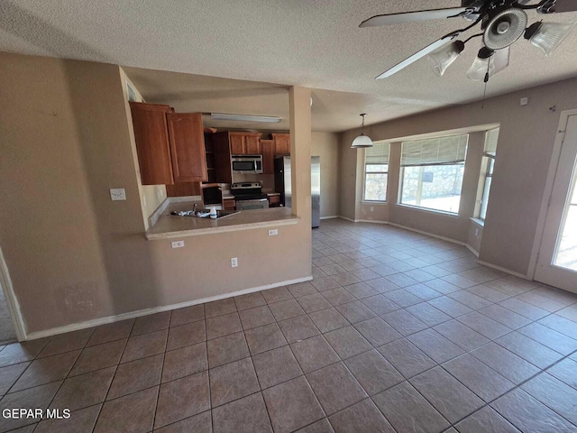 PPP10049 Paloma Dr, El Paso, TX 79924 - kitchen featuring appliances with stainless steel finishes, brown cabinets, a textured ceiling, tile patterned floors, and baseboards