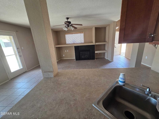 PPP10049 Paloma Dr, El Paso, TX 79924 - unfurnished living room featuring tile patterned flooring, a textured ceiling, a sink, built in features, and a fireplace