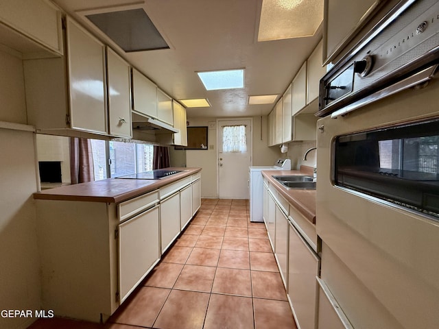 3216 Drumond Rd, El Paso, TX 79925 - kitchen featuring a sink, washer / clothes dryer, light tile patterned floors, oven, and under cabinet range hood
