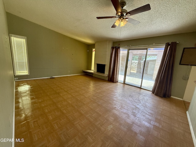 3216 Drumond Rd, El Paso, TX 79925 - unfurnished living room with baseboards, a textured ceiling, a ceiling fan, and a fireplace