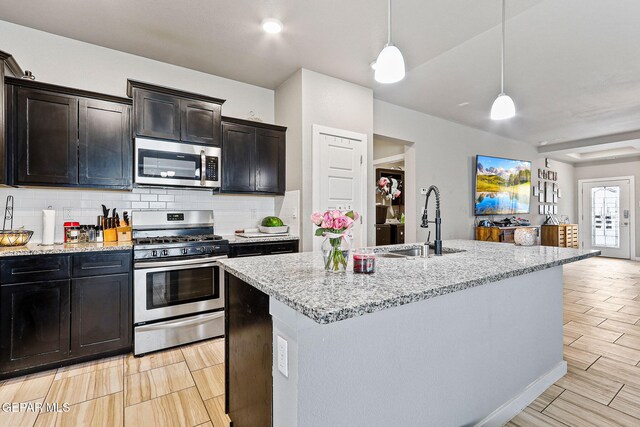13925 Lago Vista Ave, Horizon City, TX 79928 - kitchen with appliances with stainless steel finishes, a sink, tasteful backsplash, light stone counters, and decorative light fixtures