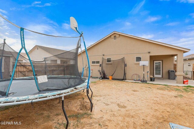 13925 Lago Vista Ave, Horizon City, TX 79928 - back of property featuring a trampoline, a patio area, and stucco siding