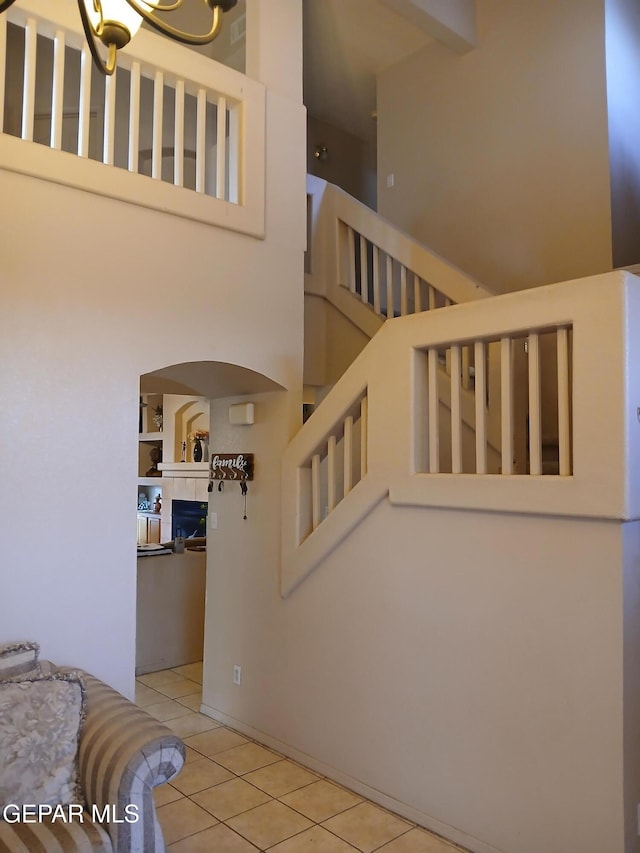 405 Santorini Ct, Socorro, TX 79927 - stairway featuring tile patterned floors, a high ceiling, and a tiled fireplace