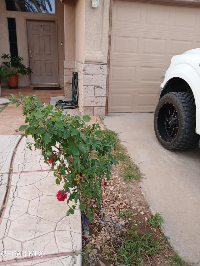 405 Santorini Ct, Socorro, TX 79927 - doorway to property featuring a garage, stucco siding, concrete driveway, and stone siding