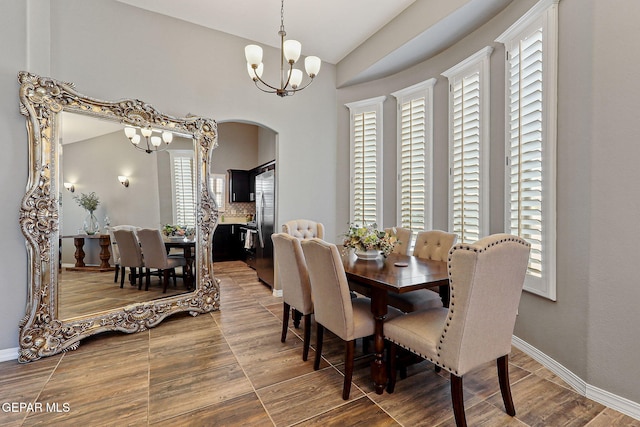 12517 Winners Cir, El Paso, TX 79928 - dining area with a chandelier, arched walkways, plenty of natural light, vaulted ceiling, and wood finished floors