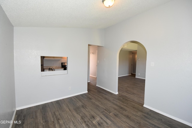 10824 Obsidian St, El Paso, TX 79924 - spare room featuring vaulted ceiling, dark wood-type flooring, baseboards, arched walkways, and a textured ceiling