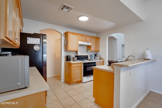 7930 Howard St, El Paso, TX 79904 - kitchen featuring gas range, under cabinet range hood, light tile patterned flooring, and arched walkways