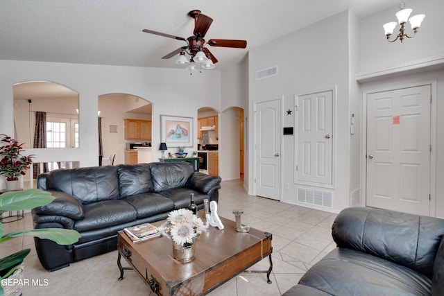 7930 Howard St, El Paso, TX 79904 - living room featuring arched walkways, a ceiling fan, light tile patterned flooring, a chandelier, and high vaulted ceiling