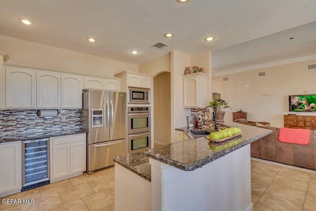 6365 Franklin Trail Dr, El Paso, TX 79912 - kitchen featuring stainless steel appliances, wine cooler, arched walkways, backsplash, and dark stone counters