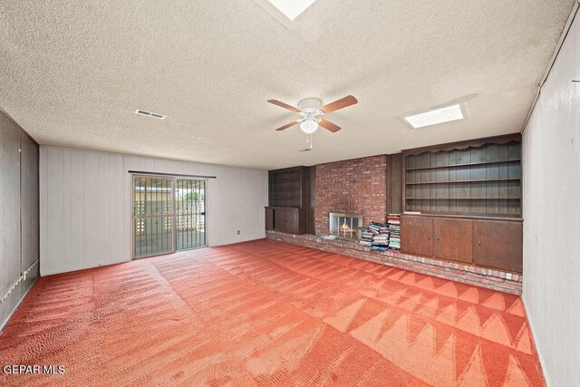5033 Royal Dr, El Paso, TX 79924 - unfurnished living room featuring a ceiling fan, a textured ceiling, a brick fireplace, built in features, and carpet flooring