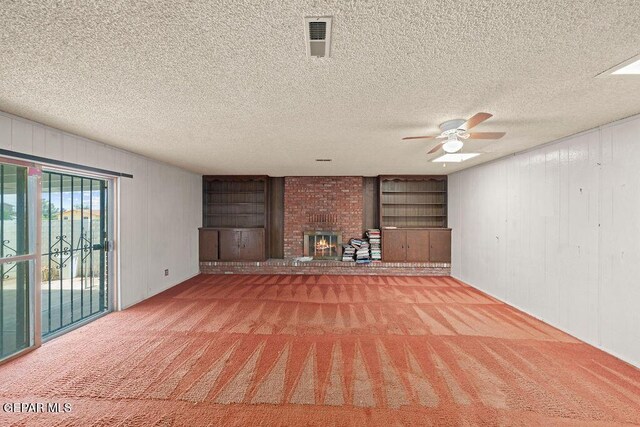 5033 Royal Dr, El Paso, TX 79924 - unfurnished living room featuring carpet, a ceiling fan, a brick fireplace, a textured ceiling, and wood walls
