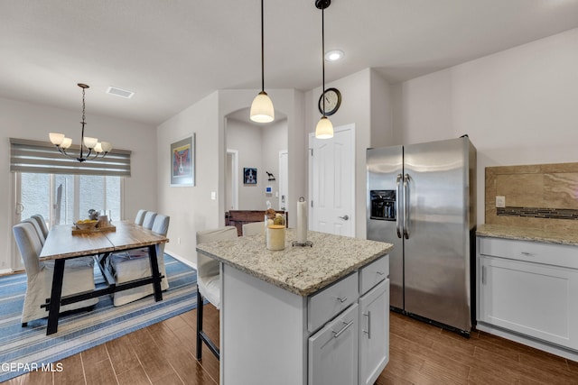 6716 Red Canyon Sage Ln, El Paso, TX 79912 - kitchen featuring stainless steel fridge with ice dispenser, dark wood-style flooring, a center island, a kitchen breakfast bar, and decorative light fixtures