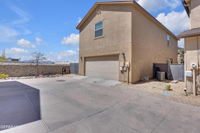 6716 Red Canyon Sage Ln, El Paso, TX 79912 - view of home's exterior featuring an attached garage, stucco siding, central AC unit, and concrete driveway