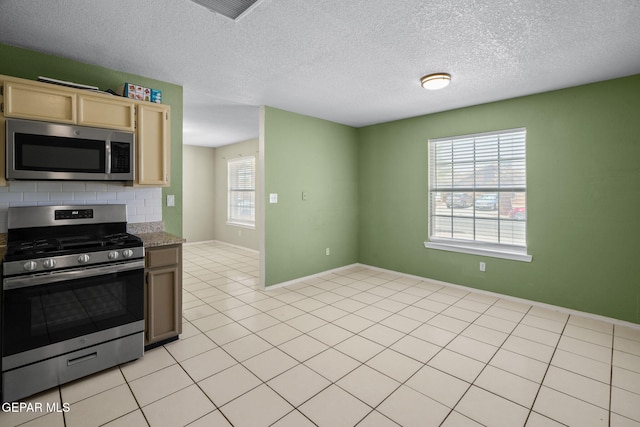 12008 Braveheart Ave, El Paso, TX 79936 - kitchen featuring appliances with stainless steel finishes, light brown cabinetry, light tile patterned floors, a textured ceiling, and backsplash