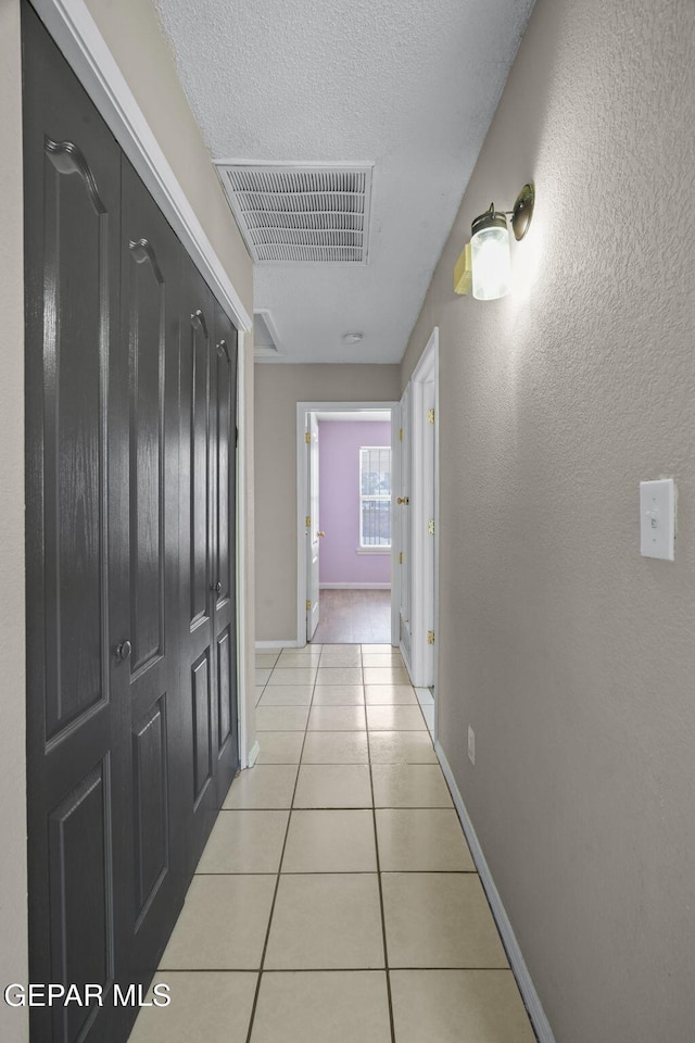 12008 Braveheart Ave, El Paso, TX 79936 - hallway with light tile patterned flooring, baseboards, and a textured ceiling