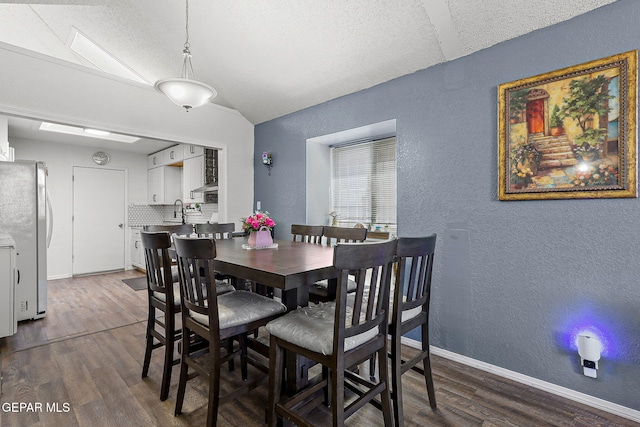 12119 Quail Harvest Ln, El Paso, TX 79936 - dining room featuring a textured wall, dark wood-style flooring, vaulted ceiling, baseboards, and a textured ceiling