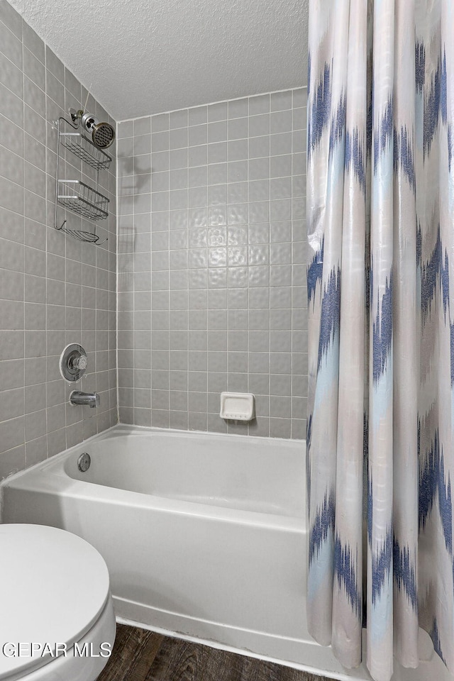 12119 Quail Harvest Ln, El Paso, TX 79936 - bathroom featuring shower / bath combo, wood finished floors, a textured ceiling, and toilet