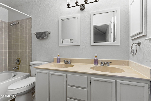 12119 Quail Harvest Ln, El Paso, TX 79936 - bathroom with double vanity, toilet, tub / shower combination, and a textured wall