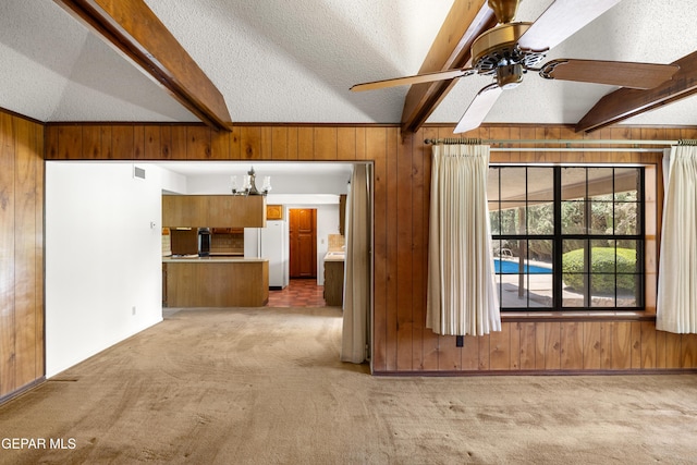 5445 Connors Ln, El Paso, TX 79932 - unfurnished living room with wood walls, light carpet, a ceiling fan, a textured ceiling, and a chandelier