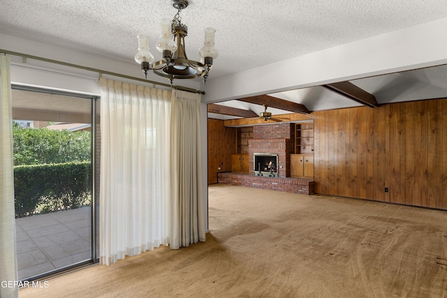 5445 Connors Ln, El Paso, TX 79932 - unfurnished living room with beam ceiling, wooden walls, carpet floors, a chandelier, and a brick fireplace