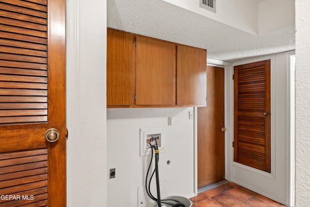 5445 Connors Ln, El Paso, TX 79932 - laundry area featuring cabinet space, hookup for a washing machine, electric dryer hookup, a textured ceiling, and light tile patterned floors