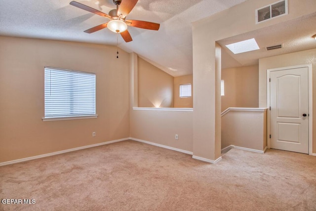 11924 Mesquite Rock Dr, El Paso, TX 79934 - carpeted empty room featuring a skylight, lofted ceiling, baseboards, a textured ceiling, and a ceiling fan