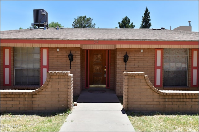 312 Caporal Ct, El Paso, TX 79932 - view of exterior entry featuring central air condition unit, roof with shingles, brick siding, and a porch