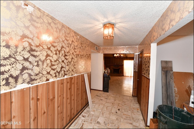 312 Caporal Ct, El Paso, TX 79932 - corridor with a textured ceiling, wainscoting, wallpapered walls, wooden walls, and a chandelier
