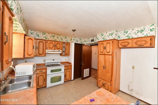 312 Caporal Ct, El Paso, TX 79932 - kitchen with white appliances, under cabinet range hood, a sink, light countertops, and wallpapered walls