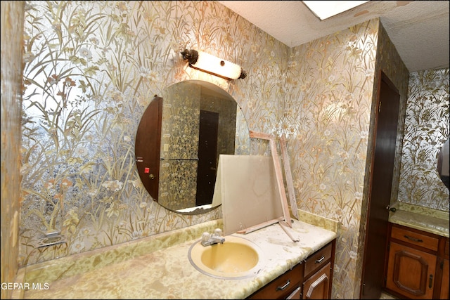 312 Caporal Ct, El Paso, TX 79932 - bathroom with wallpapered walls, a textured ceiling, and vanity