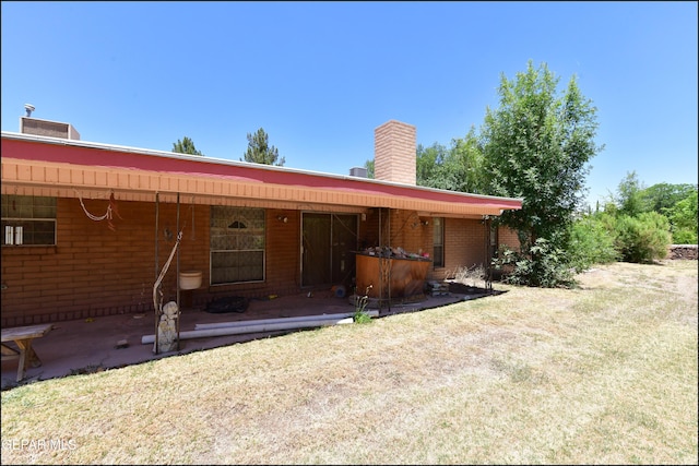 312 Caporal Ct, El Paso, TX 79932 - rear view of house featuring a chimney, brick siding, and a lawn