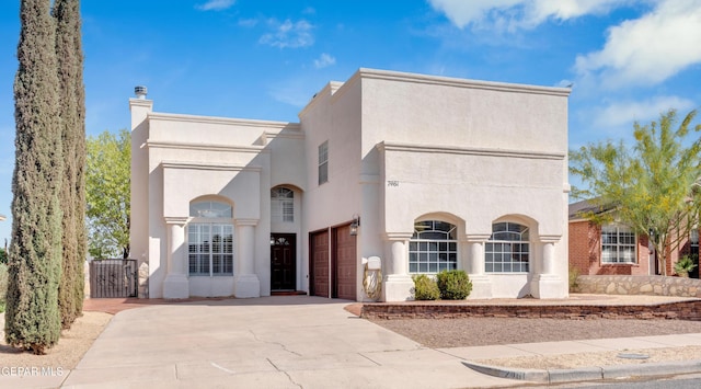 7461 Plaza Redonda Dr, El Paso, TX 79912 - view of front facade featuring concrete driveway, stucco siding, a gate, and a chimney