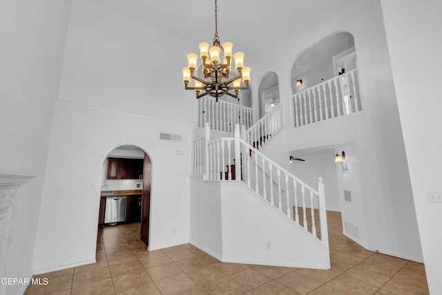 7461 Plaza Redonda Dr, El Paso, TX 79912 - stairs featuring arched walkways, a high ceiling, tile patterned flooring, a chandelier, and baseboards