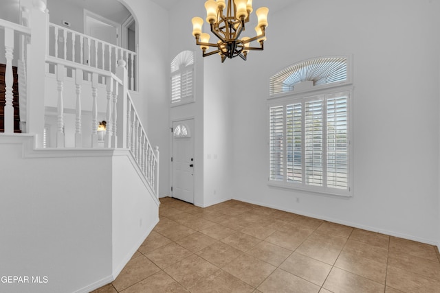7461 Plaza Redonda Dr, El Paso, TX 79912 - tiled foyer featuring a chandelier, stairway, a high ceiling, baseboards, and arched walkways