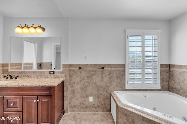 7461 Plaza Redonda Dr, El Paso, TX 79912 - full bathroom with vanity, a tub with jets, tile walls, a wainscoted wall, and tile patterned floors
