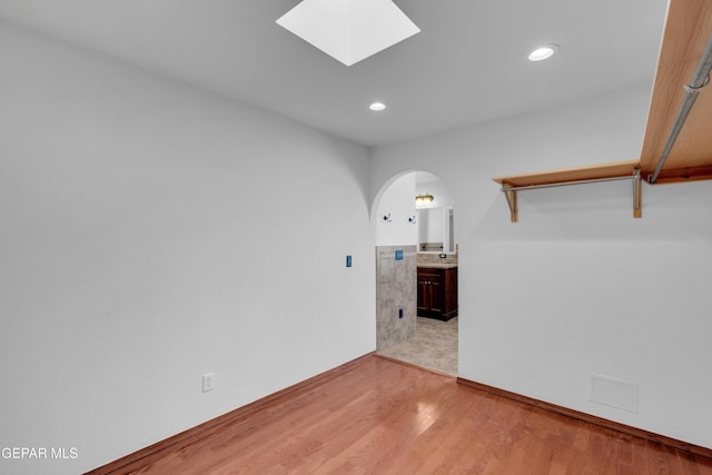 7461 Plaza Redonda Dr, El Paso, TX 79912 - empty room with arched walkways, wood finished floors, recessed lighting, and a skylight