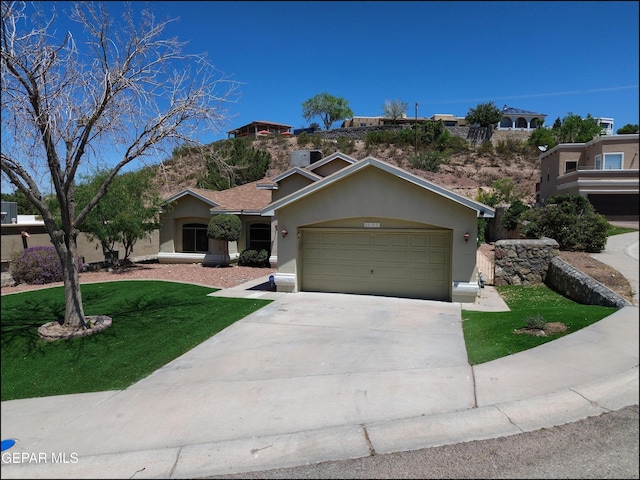 6609 El Poste Ct, El Paso, TX 79912 - view of front of home with a front yard, an attached garage, stucco siding, and concrete driveway