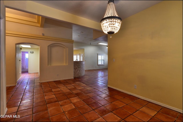 6609 El Poste Ct, El Paso, TX 79912 - empty room with tile patterned floors, arched walkways, a chandelier, and baseboards