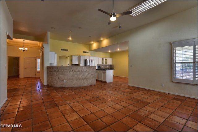 6609 El Poste Ct, El Paso, TX 79912 - kitchen with freestanding refrigerator, a peninsula, dark countertops, white cabinets, and a chandelier