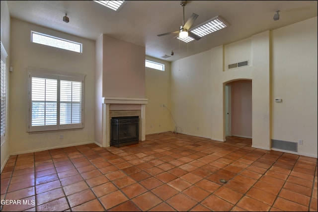 6609 El Poste Ct, El Paso, TX 79912 - unfurnished living room with a ceiling fan, a towering ceiling, a fireplace, arched walkways, and light tile patterned flooring