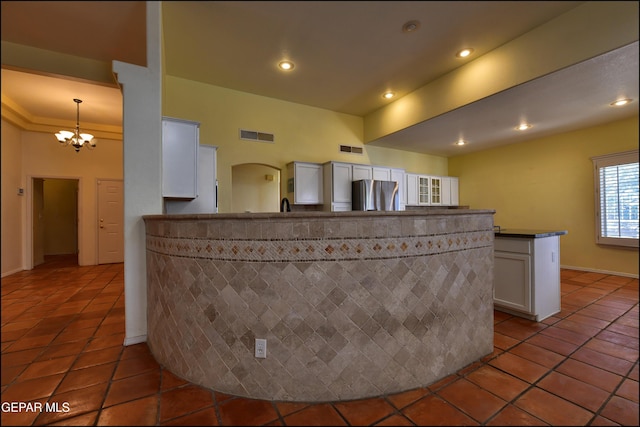 6609 El Poste Ct, El Paso, TX 79912 - kitchen with freestanding refrigerator, a chandelier, a peninsula, tile patterned floors, and white cabinetry