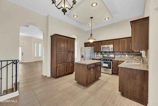 3199 Red Maple Dr, El Paso, TX 79938 - kitchen with stainless steel appliances, arched walkways, a sink, light stone counters, and tasteful backsplash