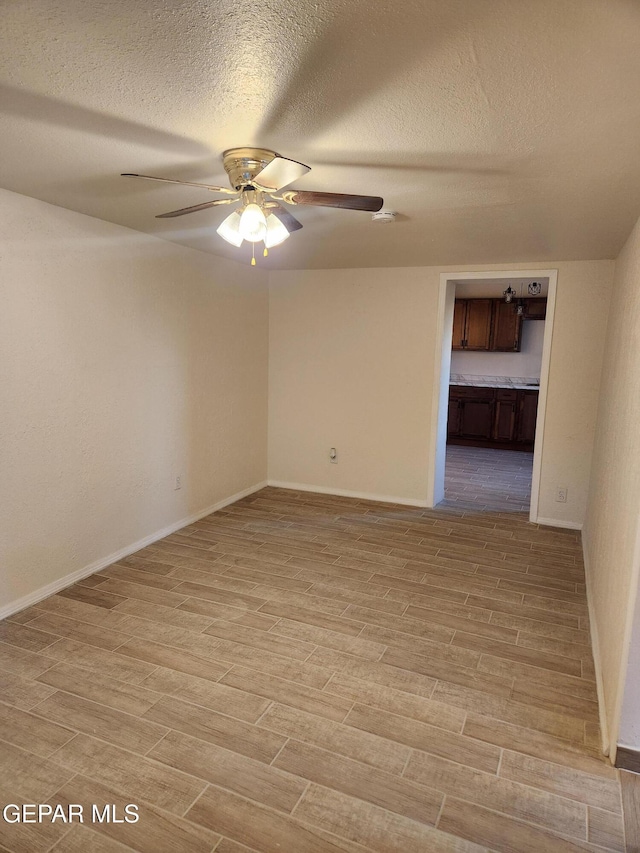 4122 Cumberland Ave, El Paso, TX 79903 - empty room featuring a ceiling fan, a textured ceiling, light wood-style flooring, and baseboards