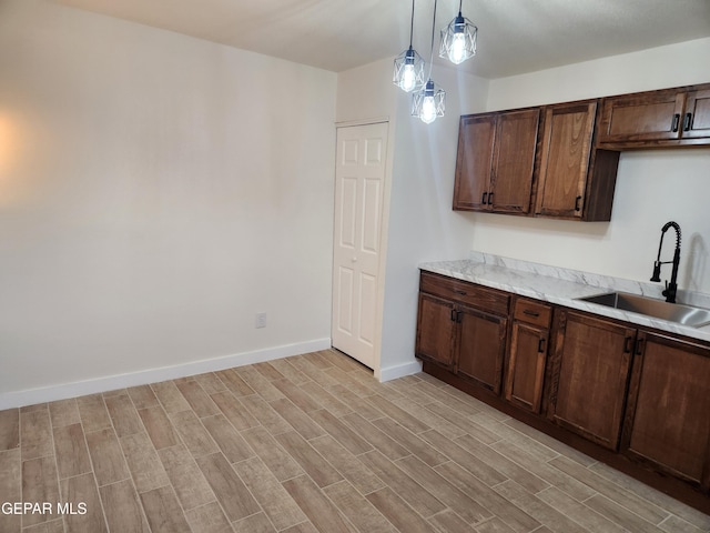 4122 Cumberland Ave, El Paso, TX 79903 - kitchen featuring a sink, decorative light fixtures, light wood-style flooring, and dark brown cabinets